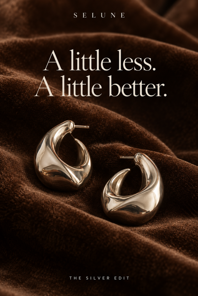 Silver earrings on brown velvet with the headline A little less. A little better